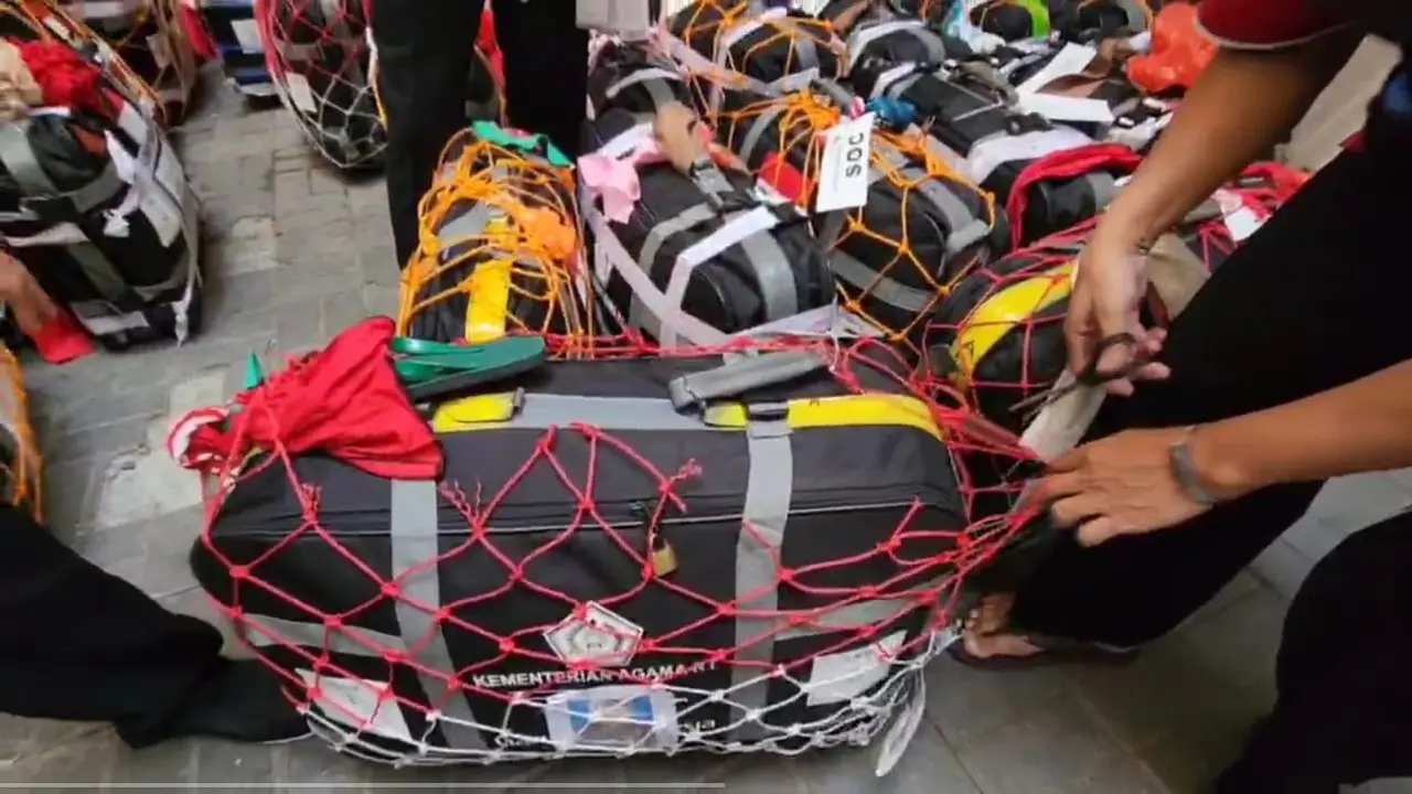 Petugas menggunting jaring koper jemaah haji Indonesia. (Liputan6.com/Mevi Linawati)