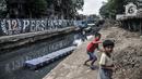 Anak-anak bermain di sekitar Kali Sentiong, Kecamatan Johar Baru, Rabu (22/9/2021). Pengerukan lumpur ini merupakan bagian dari program normalisasi guna memperdalam aliran Kali Sentiong. (merdeka.com/Iqbal S. Nugroho)