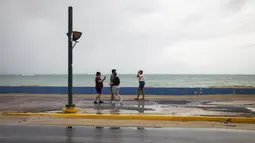 Sekelompok wisatawan berjalan di dekat laut sebelum kedatangan Badai Tropis Fiona di San Juan, Puerto Rico, Sabtu (17/9/2022). Setelah dari Puerto Rico, Fiona diproyeksikan melintasi Republik Dominika pada Senin mendatang dengan ancaman hujan deras yang berpotensi memicu banjir bandang atau longsor. (AP Photo/Alejandro Granadillo)