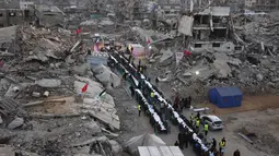 Lentera Ramadan kecil dan lampu hias yang terpasang di antara reruntuhan bangunan dan tumpukan puing, membawa sukacita dan kelegaan saat waktu berbuka puasa tiba. Tampak dalam foto, warga Palestina berkumpul untuk berbuka puasa bersama yang diselenggarakan oleh Yayasan IHH Turki, di tengah reruntuhan bangunan yang hancur di Kota Gaza pada Rabu 18 Februari 2026. (Omar AL-QATTAA/AFP)