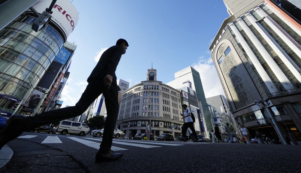 Warga yang mengenakan masker untuk membantu mengekang penyebaran COVID-19 berjalan di sepanjang penyeberangan pejalan kaki di Tokyo, Jepang, Selasa (27/7/2021). Tokyo melaporkan jumlah kasus harian COVID-19 tertinggi beberapa hari setelah Olimpiade dimulai. (AP Photo/Eugene Hoshiko)