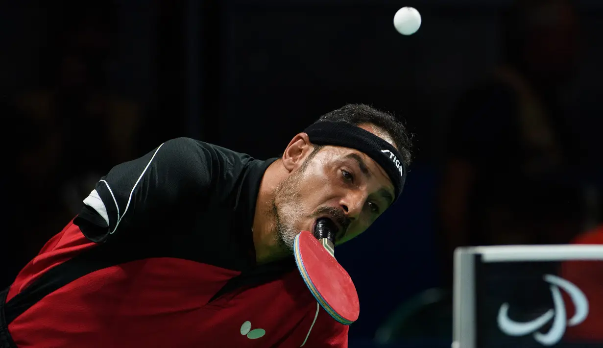 Ekspresi atlet Mesir, Ibrahim Hamadtou saat hendak memukul bola menggunakan mulutnya ke arah atlet Jerman, Thoma Rau pada cabang tenis meja tunggal putra di ajang Paralimpiade 2016, Rio de Janeiro, 9 September 2016. (Thomas Lovelock/OIS/IOC via AFP)