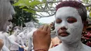 Para pemuda melukis diri mereka untuk persiapan ritual Hindu yang disebut "Grebeg" di Desa Tegallalang, Bali, Rabu (30/1). Tradisi ritual berkeliling kampung dengan riasan tubuh warna-warni itu dipercaya sebagai penangkal Roh jahat. (AP/Firdia Lisnawati)