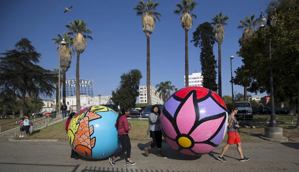 Relawan membawa bola raksasa untuk diturunkan ke danau MacArthur Park selama pameran "Spheres" di Los Angeles, California, AS (21/8/2015). Acara ini menampilkan sekitar 3.000 bola raksasa yang dihias oleh para relawan. (REUTERS/Mario Anzuoni)