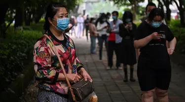 Warga mengenakan masker menunggu dalam barisan untuk tes virus corona di lingkungan di Wuhan, provinsi Hubei, Jumat (15/5/2020). Tes massal yang ditargetkan dalam 10 hari ini akibat adanya pasien Virus Corona baru di Wuhan, setelah sebulan lebih tidak ada laporan kasus baru. (Hector RETAMAL/AFP)