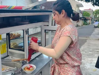 Pedangdut Dewi Perssik sedang membuat sendiri bakso yang dijual di depan rumah orangtuanya. Dewi Perssik memang sedang berada di kampung halamannya di Jember. (Youtube/Dewi Perssik)