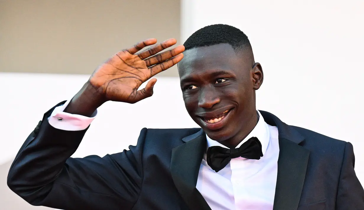 Khaby Lame  menyapa penggemarnya saat tiba untuk pemutaran film "Il Signore Delle Formiche" (Penguasa Semut) selama Venice Film Festival 2022 ke-79 di Lido di Venesia, Italia (6/9/2022). Khaby Lame adalah yang paling banyak diikuti di TikTok mengalahkan Charli D'Amelio. (AFP/Tiziana Fabi)