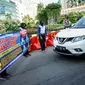 Petugas kepolisian membentangkan spanduk saat sosialisasi pelaksanaan ganjil genap di Kawasan Bundaran HI, Jakarta, Minggu (2/8/2020). Ditlantas Polda Metro Jaya kembali memberlakukan sistem ganjil genap di 25 ruas jalan protokol  DKI Jakarta mulai Senin, 3 Agustus 2020. (Liputan6.com/Faizal Fanani)