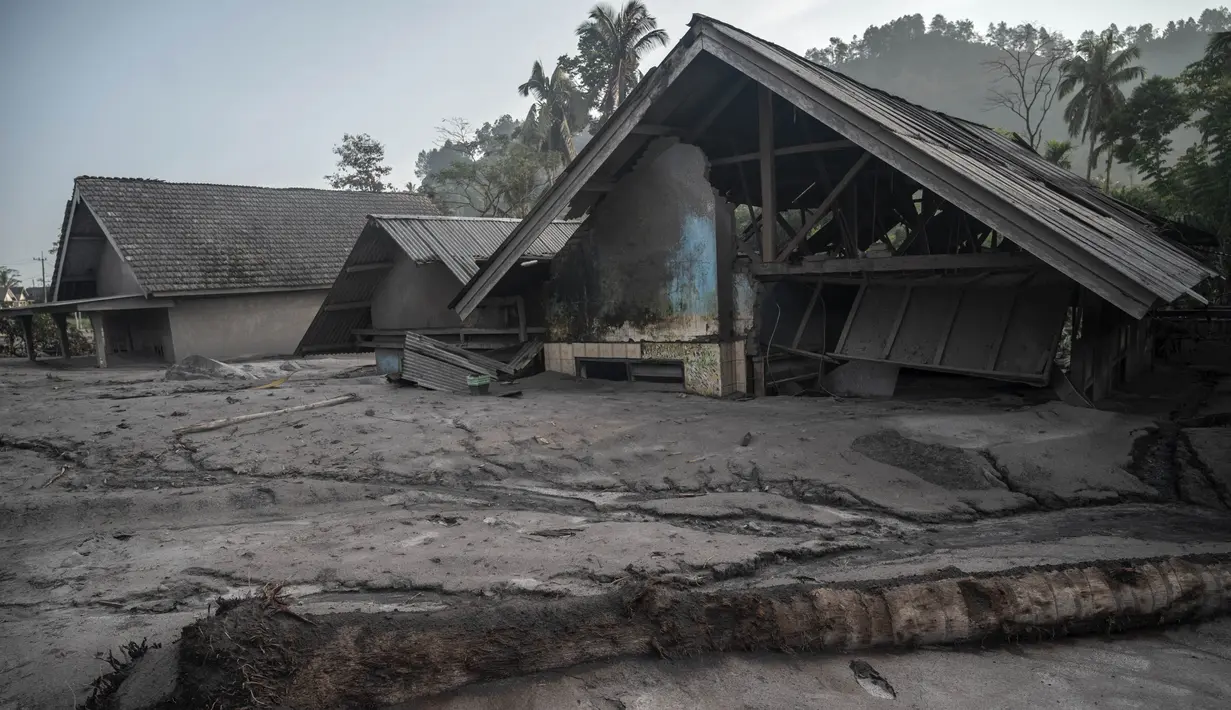 Rumah-rumah yang rusak terendam lumpur setelah letusan gunung berapi oleh Gunung Semeru di desa Kajar Kuning di Lumajang (5/12/2022). Gunung Semeru meletus pada tanggal 4 Desember memuntahkan awan abu panas setinggi satu mil dan sungai lava di sisinya sambil memicu evakuasi hampir 2.000 orang tepat satu tahun setelah letusan besar terakhirnya menewaskan puluhan orang. (AFP/Juni Kriswanto)