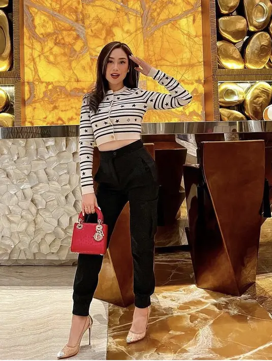 Poppy tampil dengan cardigan crop top dari Louis Vuitton, dipadukan celana hitam dan heels dari Christian Louboutin dan membawa lady Dior bag warna merah. [Instagram/@poppycapella_]