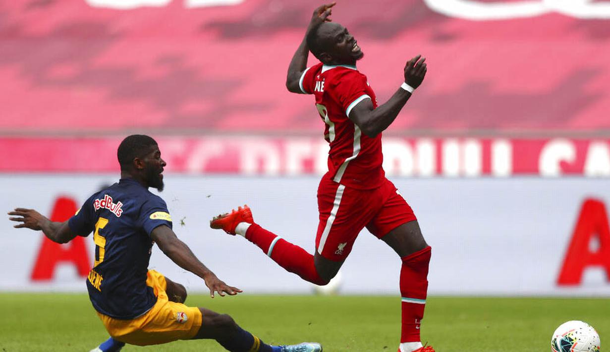 Pemain Liverpool, Sadio Mane, terjatuh saat berebut bola dengan pemain RB Salzburg, Jerome Onguene, pada laga persahabatan di Stadion Red Bull Arena, Salzburg, Selasa (25/8/2020). Kedua tim bermain imbang dengan skor 2-2. (AP Photo/Matthias Schrader)