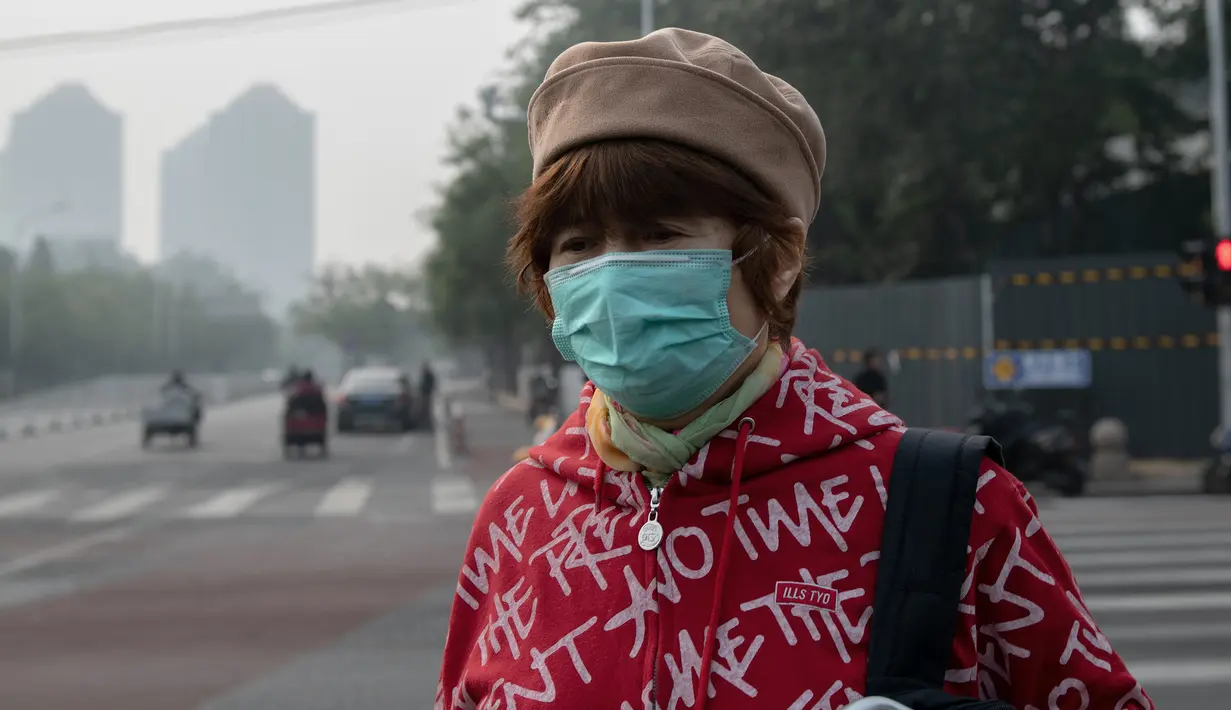 Seorang wanita beraktivitas mengenakan masker pelindung untuk menghindari polusi udara buruk di Beijing (22/10). (AFP Photo/Nicolas Asfaouri)