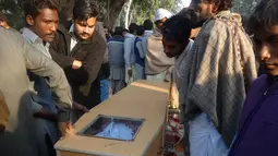 Peti jenazah korban tewas akibat minuman keras oploson di Toba Tek Singh, sekitar 338 km dari Islamabad, Selasa (27/12). Sebanyak 24 orang di kalangan kelompok kecil Kristen di Pakistan tewas setelah mengonsumsi miras oplosan saat perayaan Natal (STR/AFP)