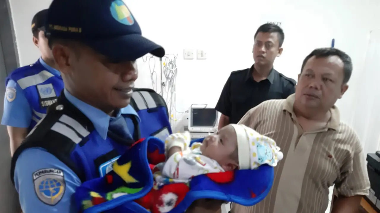 Seorang petugas Avsec menggendong bayi yang ditemukannya di Jalan Perimeter Selatan, Bandara Soetta, Senin (26/11/2018)