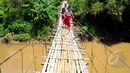 Sejumlah siswa SD harus melewati jembatan gantung beresiko di atas kali Ciliwung untuk menuju ke sekolah, Jakarta, Selasa (17/3/2015). Jembatan tersebut menghubungkan Kelapa Dua Depok dengan Lenteng Agung (Liputan6.com/Yoppy Renato)