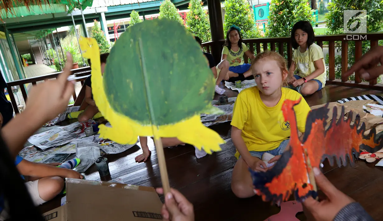 Siswa sedang mendengar penjelasan dari pelukis wayang sebelum mewarnai wayang kulit di Jakarta Intercultural School (JIS) Elementary, Jakarta, Kamis (2/11). Kegiatan ini merupakan bagian dari JIS cultural week. (Liputan6.com/Fery Pradolo)