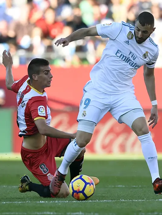 Pemain Girona, Pere Pons (kiri) berusaha menahan laju pemain Real Madrid, Karim Benzema pada lanjutan La Liga Santander di Municipal de Montilivi stadium, Girona , (29/10/2017). Madrid kalah 1-2. (AFP/Josep Lago)