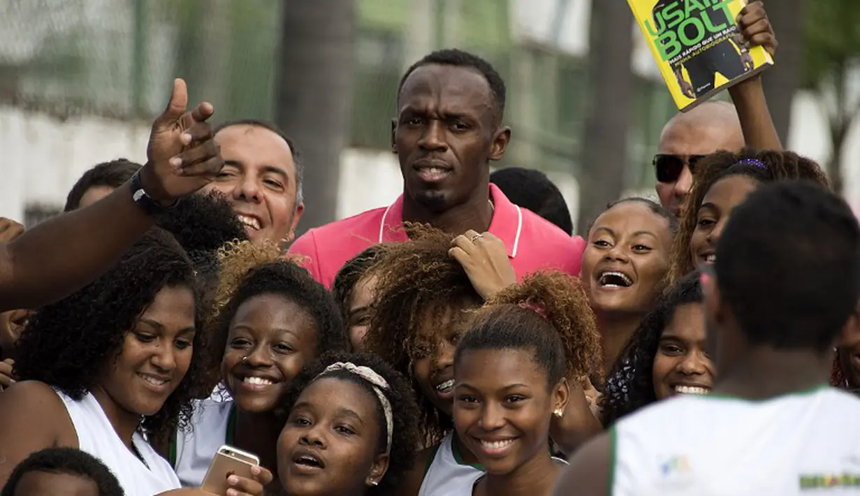 3.	Sprinter Jamaika juara Olimpiade,Usain Bolt, berfoto dengan anak-anak saat mengunjungi kompleks olah raga Mangueira, Rio de Janeiro, Brasil. Jumat (16/4)