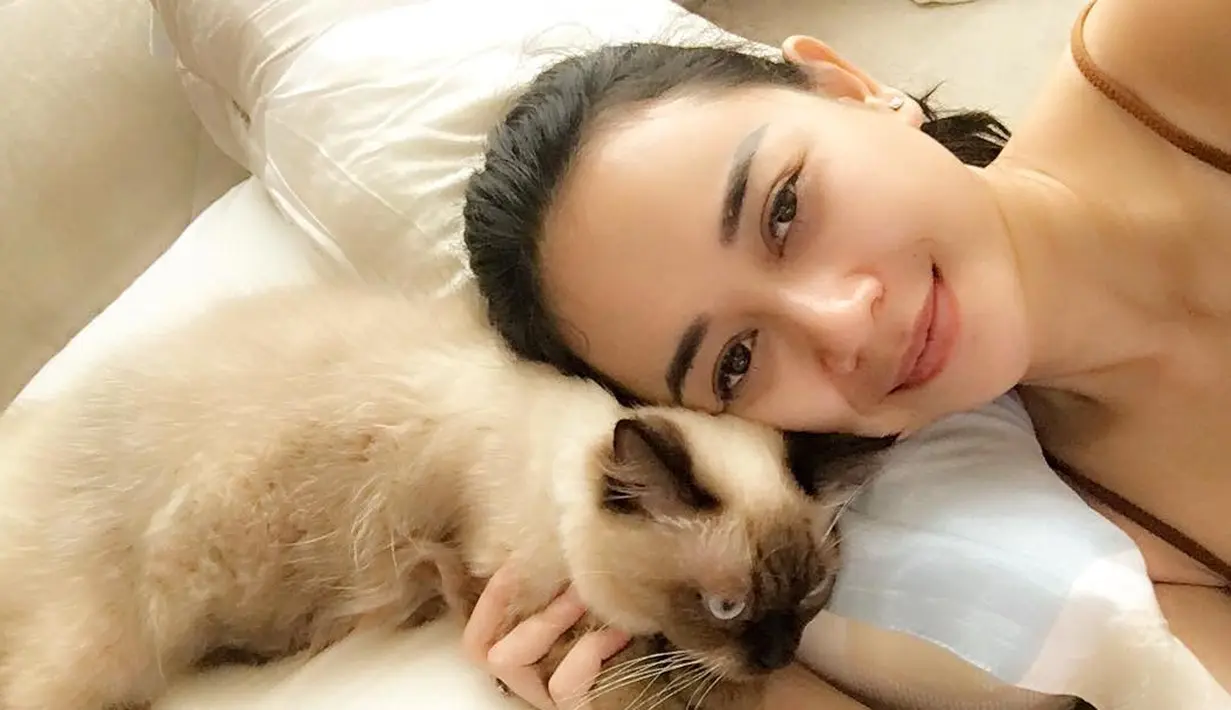 Meskipun tampil natural, namun Aura Kasih tetap cantik menawan. Ia terlihat berpose di atas ranjang bersama kucing kesayangannya. (FOto: instagram.com/aurakasih)
