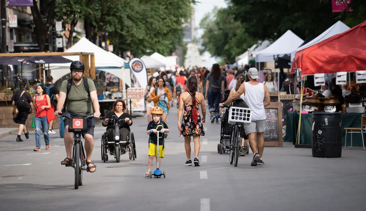 Orang-orang berjalan di sepanjang Saint-Laurent Boulevard saat Festival Mural Montreal di Quebec, Kanada, 16 Juni 2022. Pada bulan Juni ini, lusinan seniman sibuk melukis pada dinding raksasa dalam edisi kesepuluh Festival Mural Montreal. (Paola Chapdelaine/AFP)