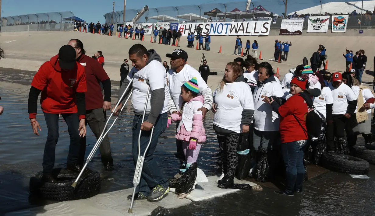 Sejumlah orang melintasi sungai untuk bertemu dengan keluarga dan kerabat mereka di perbatasan Meksiko-AS di Ciudad Juarez, Meksiko (28/1). (AP Photo/Christian Torres)