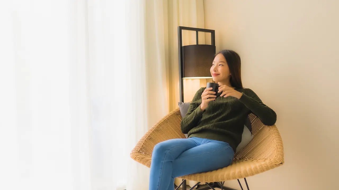 Seorang perempuan sedang menikmati secangkir kopi di sebuah kursi (Foto Dok: Freepik/lifeforstock)