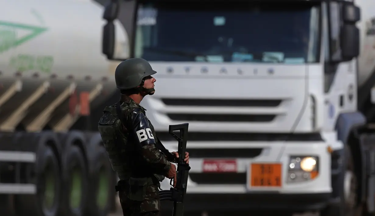Tentara mengawal truk kargo yang mengangkut BBM penerbangan ke bandara internasional selama aksi mogok sopir truk di Brasilia, Brasil, Senin (28/5). Presiden Brasil Michel Temer akhirnya menurunkan kembali harga BBM. (AP Photo/Eraldo Peres)