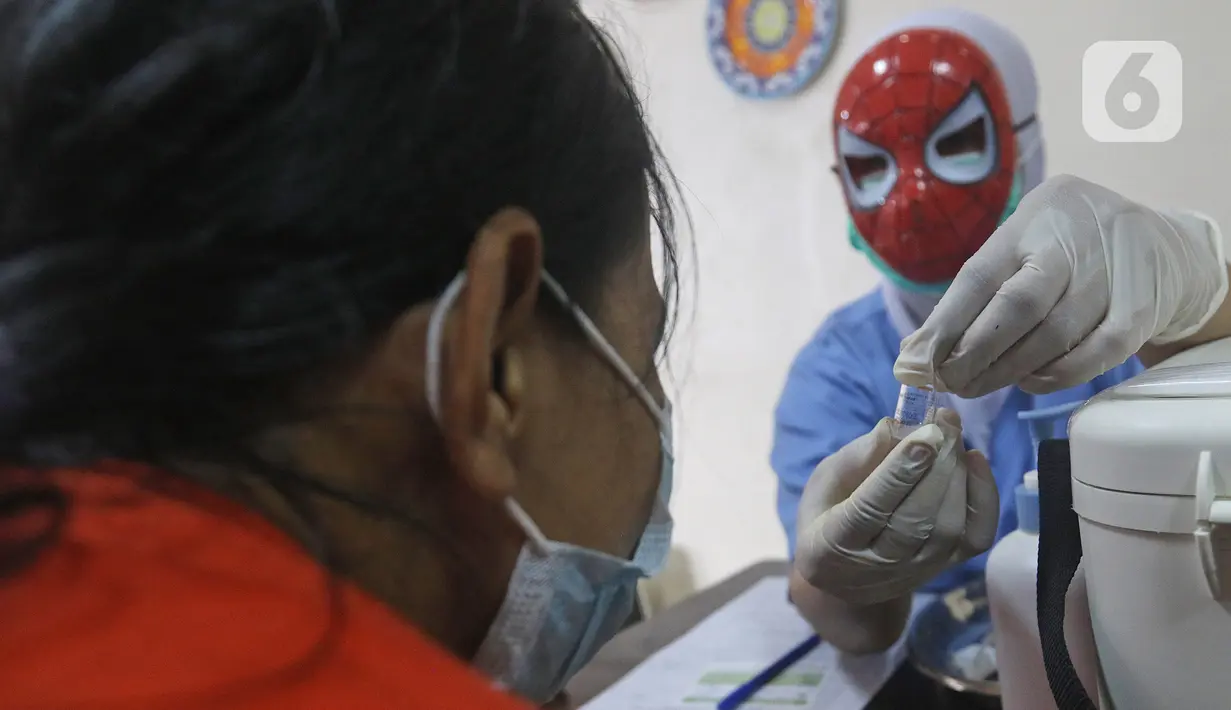 Tenaga kesehatan bertopeng superhero memperlihatkan botol vaksin covid-19 kepada orang tua anak saat vaksinasi anak usia 6-11 tahun di RSIA Tambak, Jakarta, Rabu (22/12/2021). Penggunaan topeng superhero dimaksudkan menarik minat anak-anak yang mengikuti vaksinasi. (lLiputan6.com/Herman Zakharia)