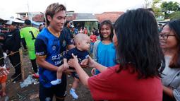 Pesepak bola profesional Asri Akbar tampak ramah melayani permintaan fans yang meminta sang pemain untuk menggendong anaknya. Tarkam membuat warga mempunyai kesempatan melihat lebih dekat para pemain yang biasa dilihat di layar kaca kini bisa langusung berada dihadapannya. (Bola.com/M Iqbal Ichsan)
