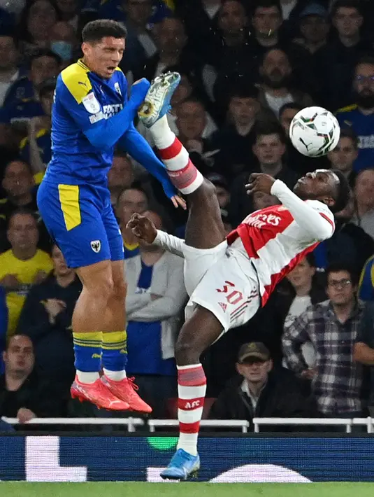 Pemain Arsenal Eddie Nketiah (kanan) berebut bola dengan pemain AFC Wimbledon Henry Lawrence pada pertandingan Piala Liga Inggris di Emirates Stadium, London, Inggris, 22 September 2021. Arsenal menang 3-0. (JUSTIN TALLIS/AFP)