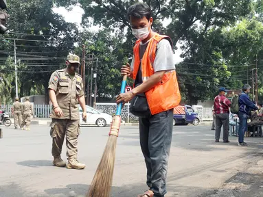 Warga menyapu jalan saat terjaring operasi tertib masker dalam rangka penerapan protokol kesehatan COVID-19 di Jalan Fatmawati, Jakarta, Kamis (10/3/2022). Pelanggar disanksi kerja sosial menyapu jalan atau denda Rp250 ribu dan menandatangani surat pernyataan tak mengulangi.(merdeka.com/Arie Basuki)