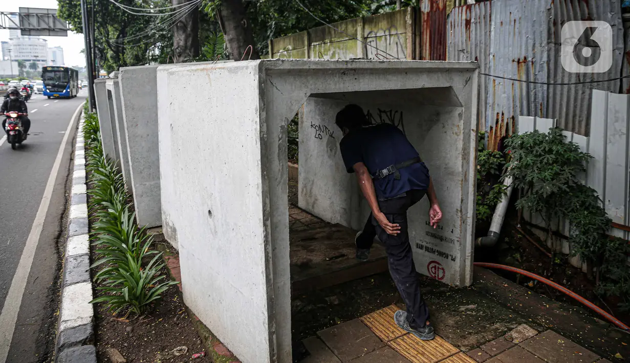 Pejalan kaki melintas di antara beton saluaran air yang berada di jalur pedestrian kawasan Gatot Subroto, Jakarta, Selasa (21/12/2021). Selain mengganggu kenyamanan, keberadaan beton saluran air tersebut juga dapat membahayakan pejalan kaki yang melintas. (Liputan6.com/Faizal Fanani)