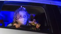 Seorang anak yang mengenakan masker menonton pertunjukan dari dalam mobil di taman hiburan horor Hopi Hari, pinggiran Vinhedo, Sao Paulo, Brasil, Jumat (4/9/2020). Karena pembatasan akibat COVID-19, taman hiburan horor Hopi Hari menampilkan pertunjukan secara drive-thru. (AP Photo/Carla Carniel)