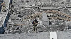 Seorang prajurit Ukraina berjalan melintasi jembatan yang hancur di kota Borodianka, barat laut Kiev pada 4 April 2022. Saat pasukan Rusia mundur, kota kecil Borodianka, 50 km barat laut Kiev, menjadi reruntuhan. (Sergei SUPINSKY / AFP)