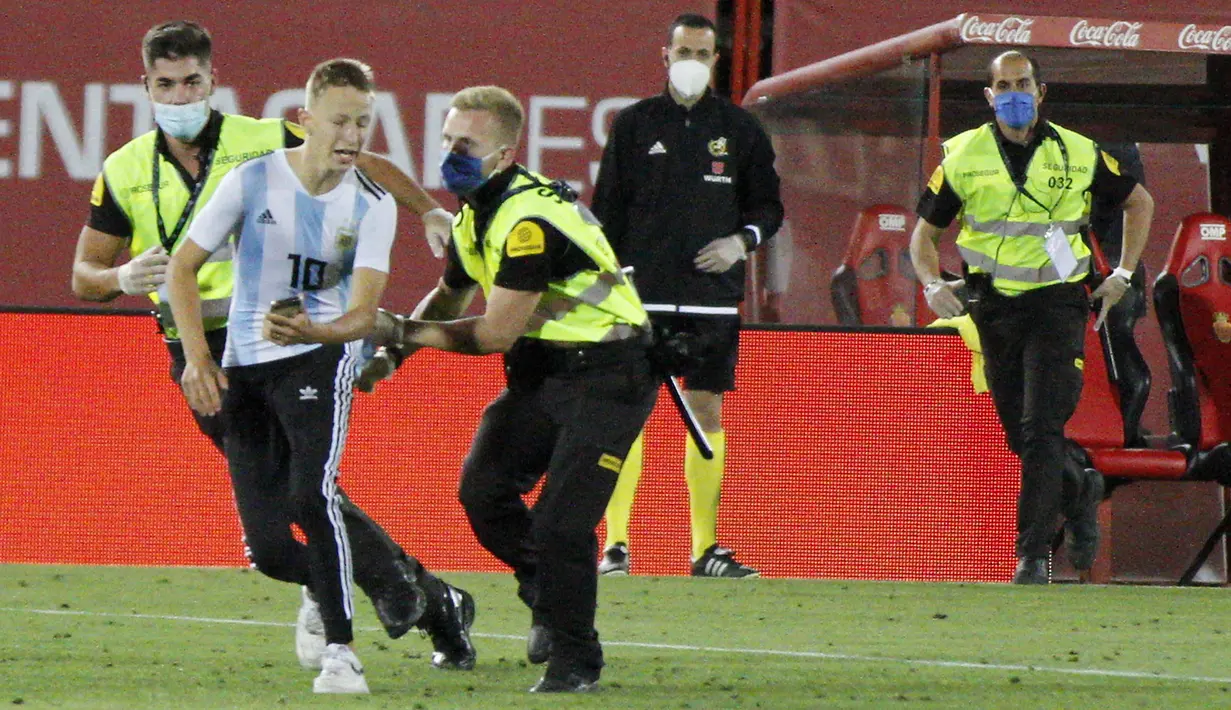 Petugas keamanan menangkap seorang penyusup yang masuk ke lapangan saat pertandingan La Liga antara Mallorca dengan FC Barcelona di Son Moix Stadium, Palma de Mallorca, Spanyol, Sabtu (13/6/2020). Dalam pertandingan tersebut Barcelona mengalahkan Mallorca dengan skor 4-0. (AP Photo/Francisco Ubilla)