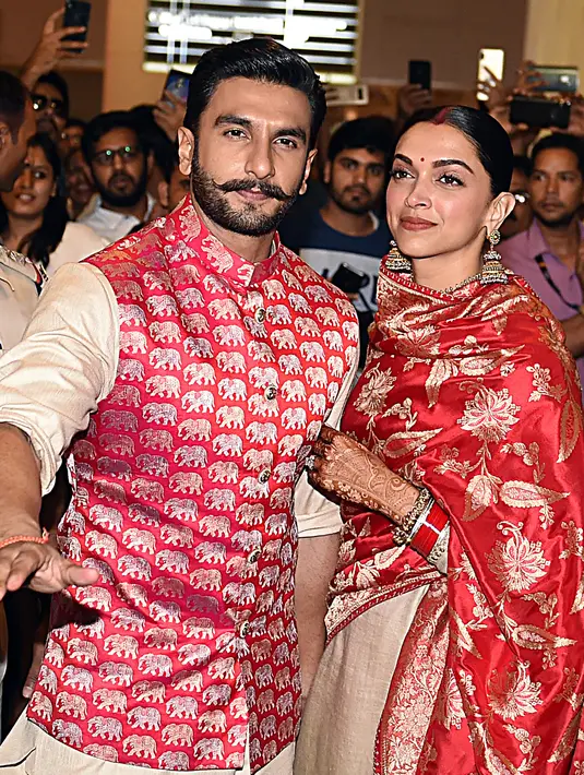 Pasangan bintang Bollywood India, Ranveer Singh dan Deepika Padukone menyapa penggemar yang menyambut mereka di bandara Mumbai, Minggu (18/11). Setelah pacaran selama 5 tahun, Deepika dan Ranveer akhirnya resmi melangsungkan pernikahan di Italia. (AFP)