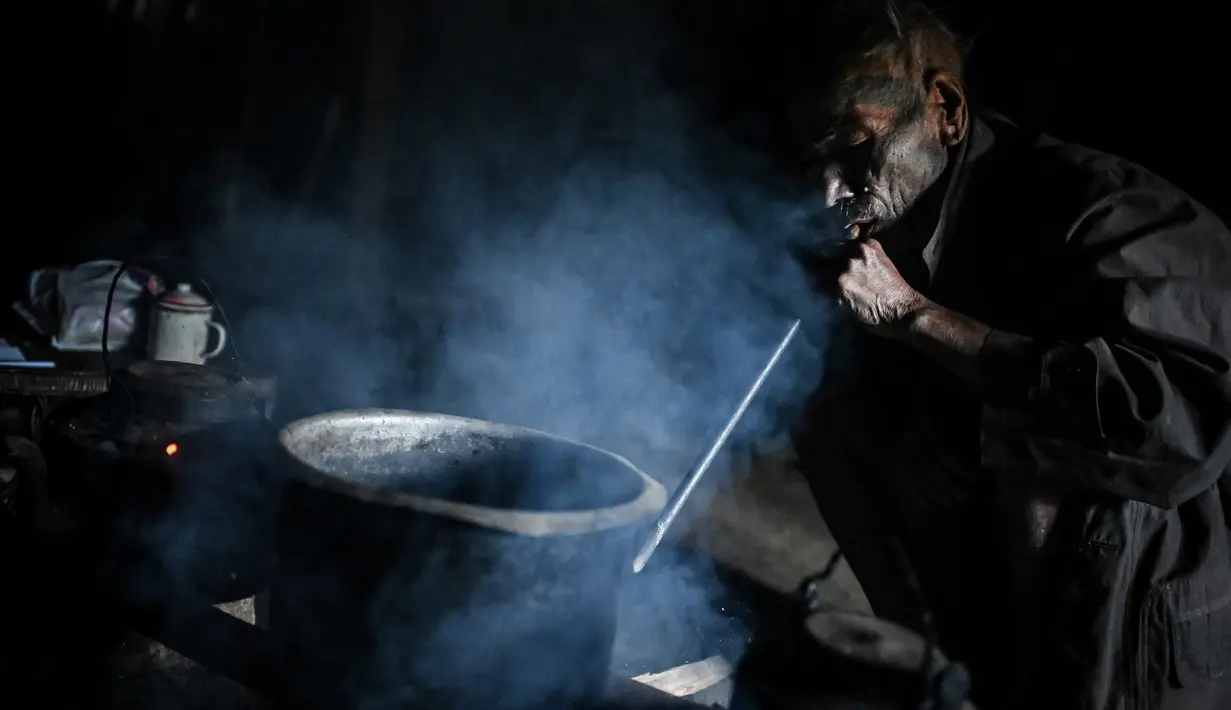 Nok Tan (75), seorang suku Konyak yang bertato memasak dalam rumahnya di sebuah desa di wilayah Sagaing, Myanmar, 9 Februari 2020. Tato bisa menandakan identitas suku, pencapaian kehidupan atau penyelesaian ritual perjalanan. (Ye Aung THU/AFP)