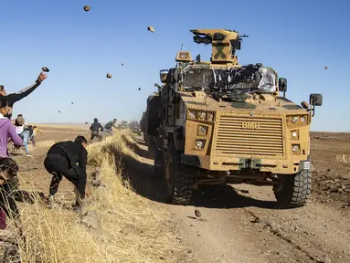 Sejumlah warga Kurdi melemparkan batu ke kendaraan militer Turki di dekat kota Al-Muabbadah, bagian timur laut Hassakah, Suriah (8/11/2019). Pelemparan batu terjadi saat militer Turki melakukan konvoi dengan militer Rusia. (AFP/Delil Souleiman)