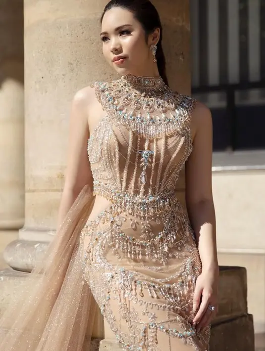 Gwen mengenakan dress warna nude dengan model halter neck yang dihiasi beads. Gaun model cut out samping ini dilengkapi train warna serasi dengan tampilan shimmernya. [@nancywarrencouture]