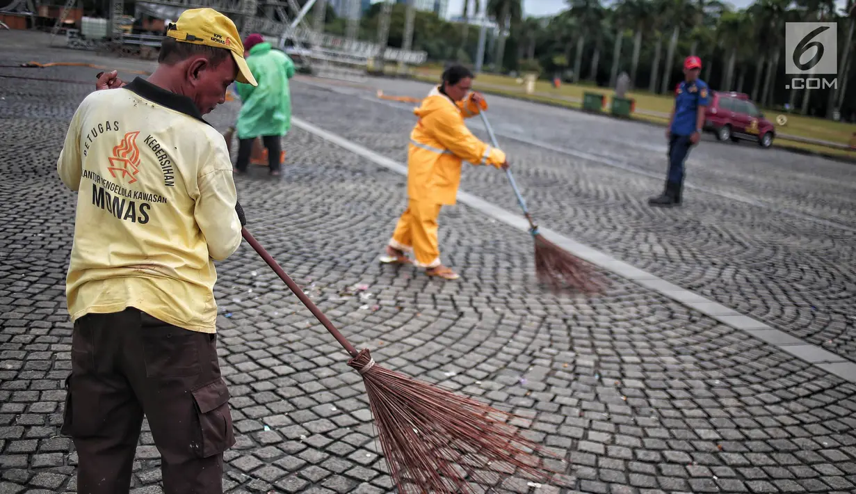 Petugas kebersihan membersihkan sisa sampah usai perayaan Tahun Baru 2019 di Monas, Jakarta, Selasa (1/1). Total sampah di DKI Jakarta saat perayaan Tahun Baru 2019 berkurang dari tahun lalu. (Liputan6.com/Faizal Fanani)