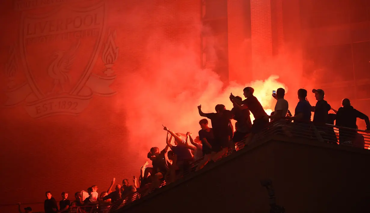 Para fans merayakan Liverpool memenangkan gelar juara Liga Primer Inggris setelah kemenangan Chelsea 2-1 atas Manchester City, di luar stadion Anfield di Liverpoo (25/6/2020). Pasukan Jurgen Klopp memastikan gelar liga ke-19 untuk klub dengan rekor tujuh pertandingan tersisa. (AFP Photo/Oli Scarff)