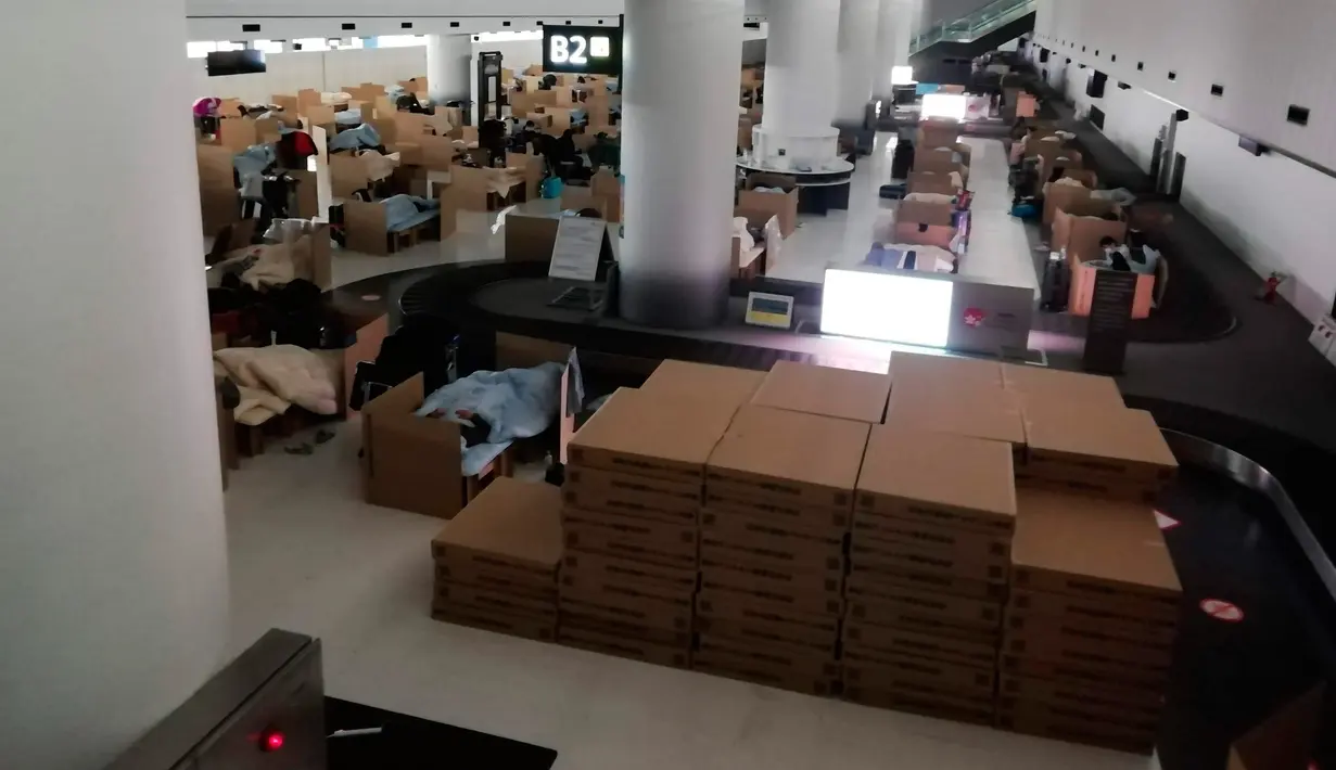 Orang-orang menunggu hasil tes virus corona mereka di tempat tidur sementara dari kotak kardus di Bandara Internasional Narita di Narita, dekat Tokyo, 8 April 2020. Di samping tempat tidur kardus, disediakan troli untuk tempat minuman dan makanan ringan, termasuk onigiri. (Naohiro Katsuta via AP)