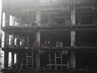 Anggota Pasukan Tanggap Bencana Nasional dan petugas pemadam kebakaran memeriksa sebuah gedung komersial sehari setelah kebakaran terjadi di New Delhi, India, Sabtu (14/5/2022). Kebakaran yang melanda gedung perkantoran empat lantai di Delhi, pada Jumat 13 Mei 2022, menewaskan sedikitnya 27 orang dan melukai sedikitnya 12 orang, kata layanan darurat. (Sajjad HUSSAIN / AFP)