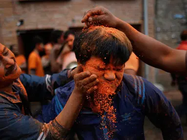Warga menaburkan bubuk vermillion saat perayaan sindoor Jatra festival di Bhaktapur, Nepal (15/4). Dalam festival tersebut warga Nepal menaburkan serbuk berwarna oranye untuk merayakan 'Sindoor Jatra'. (AP Photo/Niranjan Shrestha)