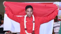 Pelari muda Indonesia, Lalu Muhammad Zohri membentangkan bendera Merah Putih saat penyambutan di Terminal 3 Bandara Soetta, Tangerang, Selasa (17/7). Lalu M Zohri meraih emas 100m putra di Kejuaraan Dunia Atletik U-20. (Liputan6.com/Helmi Fithriansyah)
