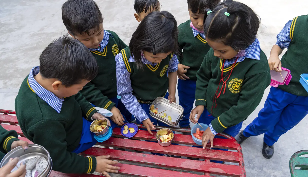 Anak-anak Tibet di pengasingan berbagi makan siang mereka saat istirahat di kelas di Sekolah Hari Desa Anak-anak Tibet di Dharmsala, India (24/3/2022). Kehidupan sekolah perlahan kembali normal setelah sempat terganggu akibat pandemi COVID-19. (AP Photo/Ashwini Bhatia)