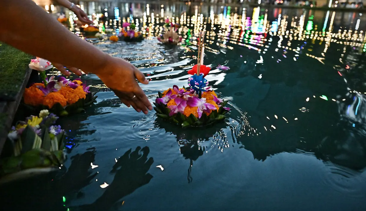 Orang-orang melepaskan lampion mengambang di kolam selama festival Loy Krathong di Bangkok (8/11/2022). Loy Krathong adalah ritual melarung wadah berbentuk lotus yang didalamnya diberi sesajen, lilin dan dupa. (AFP/Lillian Suwanrumpha)