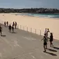 Orang-orang berjalan melewati Pantai Bondi yang kosong setelah ditutup oleh pihak berwenang di Sydney, Minggu (22/3/2020). Otoritas Australia menutup Bondi Beach  lantaran orang-orang mengabaikan larangan tidak berkumpul dalam jumlah besar untuk menekan penyebaran virus corona. (PETER PARKS/AFP)