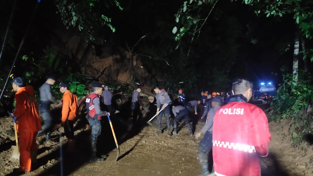Tim Sabhara Polres Tasikmalaya bersama intansi relawan lainnya tengah bahu membahu melakukan evakuasi longsoran tanah di Jalan Raya Salopa Cikatomas, Tasikmalaya. (Liputan6.com/Jayadi Supriadin)