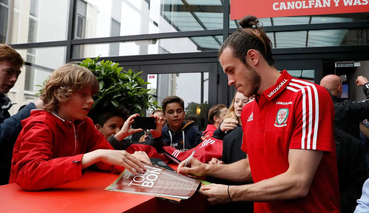 Gareth Bale memberikan tanda tangannya kepada fans saat menggelar konferensi pers jelang babak 8 besar Piala Eropa 2016, Stadium COSEC, Prancis, Rabu (29/6). Bale menyebut kini Wales sudah berada setingkat di atas Inggris. (REUTERS / Gonzalo Fuentes)